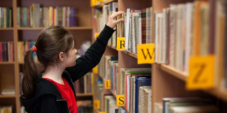 Girl looking for book in school library