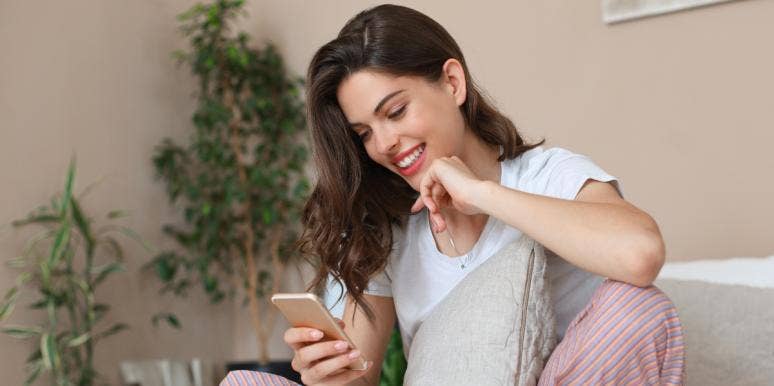 50 Cute Good Night Messages For Her woman smiling at phone in bed