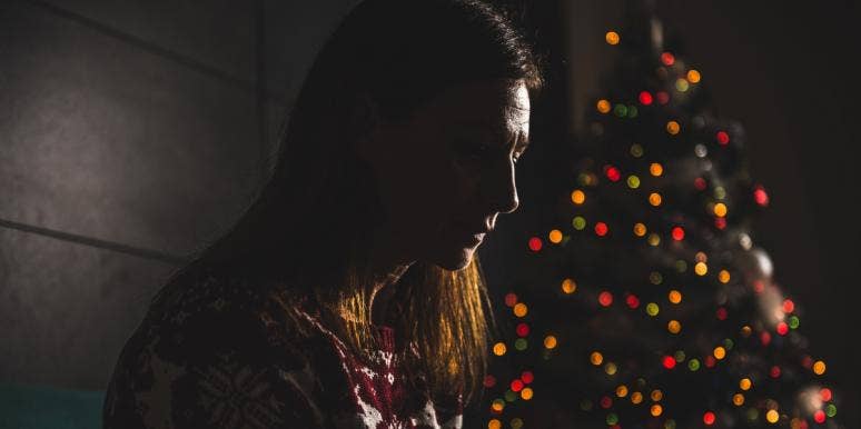 grief during the holidays grieving woman in the darkness with Christmas tree