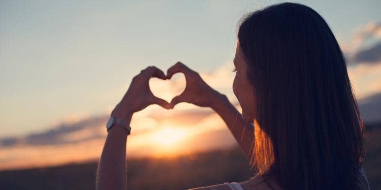 heart chakra woman making a heart in the sunset