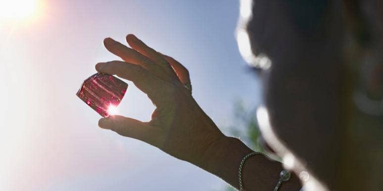 heart chakra holding out crystal under the sun