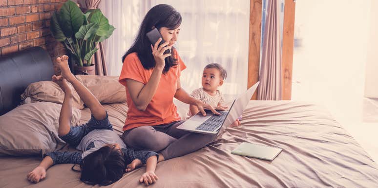 The Dreaded Stigma That Sticks To Stay-At-Home Moms woman working at home with 2 kids around