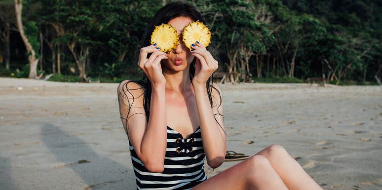 woman holding pineapples in front of her eyes