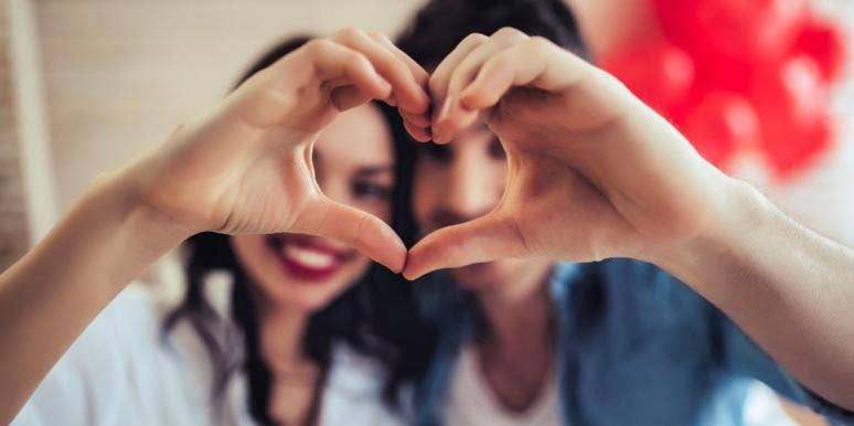 Why We Celebrate Valentine's Day — History & Origins couple holding hands in heart shape for Valentine's Day