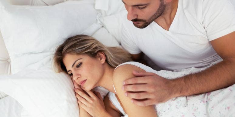 unhappy woman laying in bed with husband