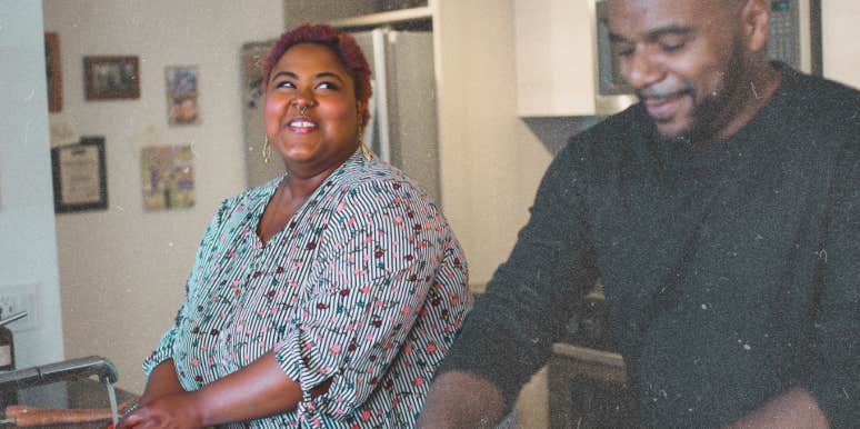 Woman staring knowingly at man while they wash dishes 