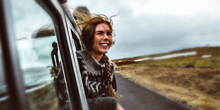 woman, smiling, hanging out of a car window in the high desert 