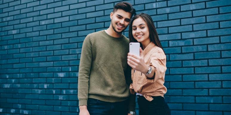 What Your Social Media Habits Weirdly Reveal About Your Relationship couple taking selfie