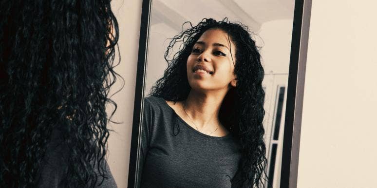 woman looking in the mirror to love herself again