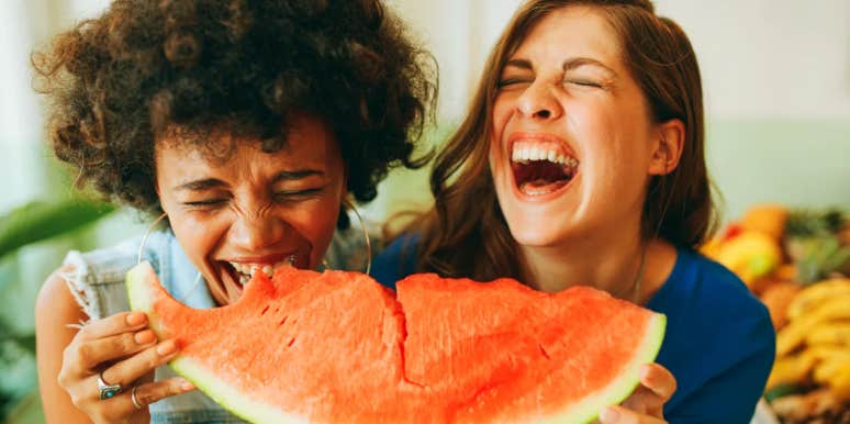 two girls laughing while eating watermelon