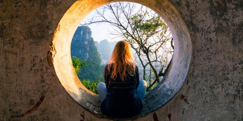 woman looking through a port hole to a beautiful view