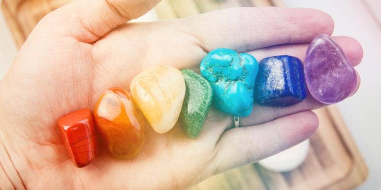 How To Unblock Your Chakra Points For Spiritual & Physical Healing hand holding rainbow colored gemstones