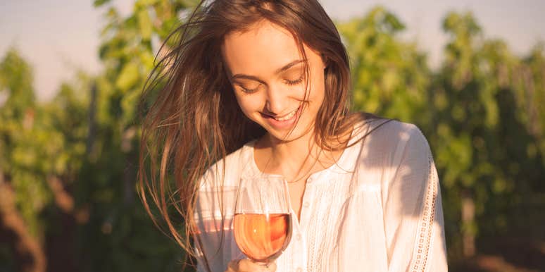 I Drink, My Guy Doesn't—And We're Happily In Love woman holds a glass of fruit alcohol in nature