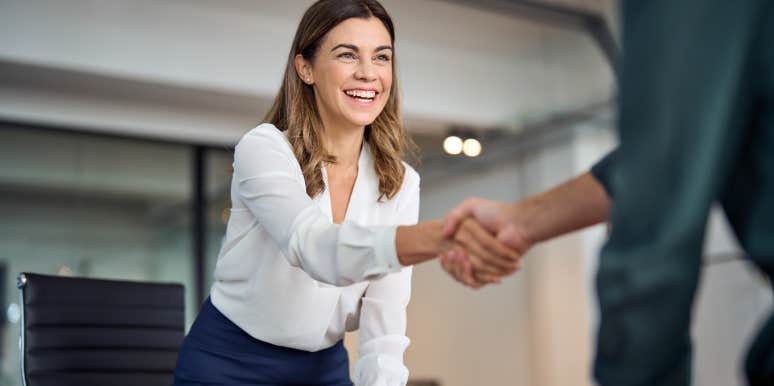 Happy business woman shaking hand of boss during job interview in office