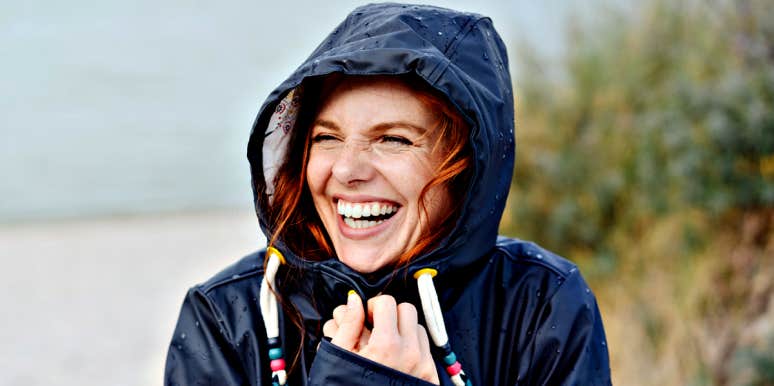 redhead woman with freckles laughing in raincoat