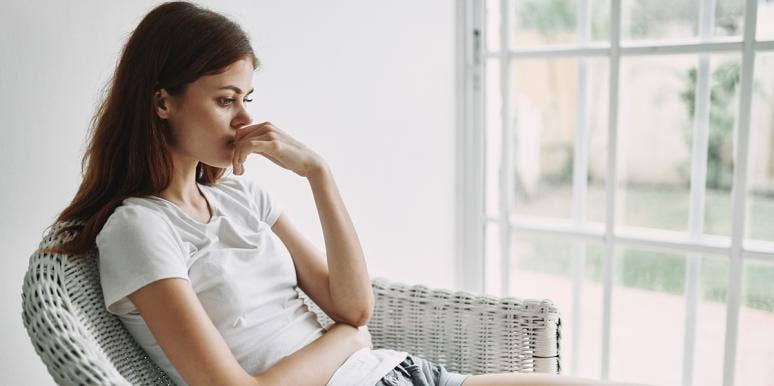 Why I Plan To Have A Kid — Even Though I Don't Want One woman in white in thought by window