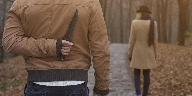 What Makes Someone Become A Serial Killer man standing behind a woman with a knife behind his back