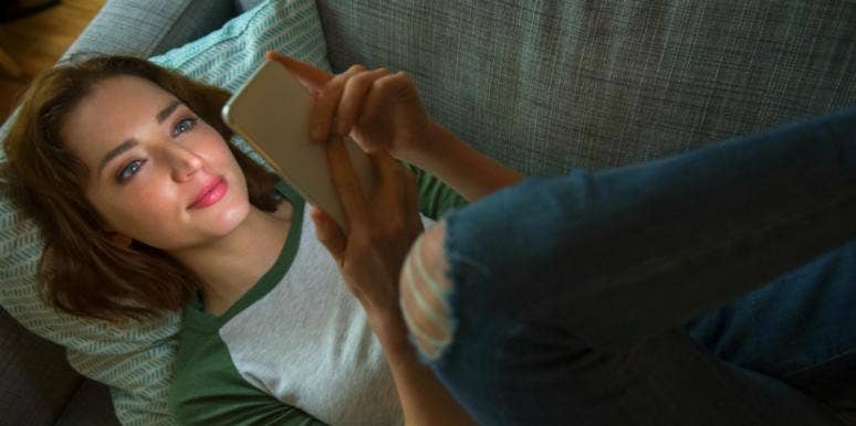 woman laying on the couch playing on phone