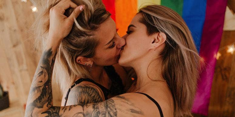 two women kissing in front of rainbow flag