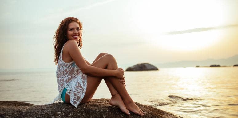 life goes on after divorce smiling woman sitting by the ocean at sunset