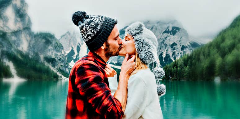 couple kissing by a mountain lake
