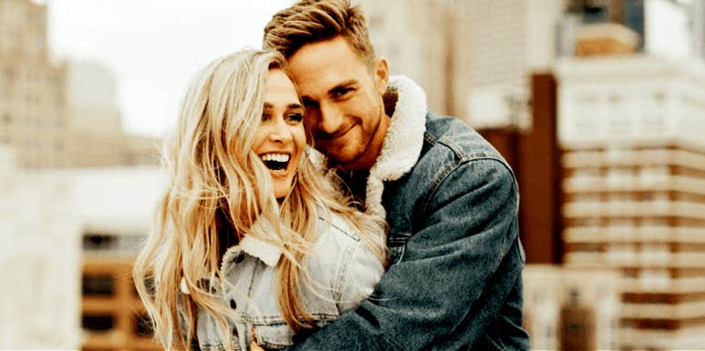 white couple with blonde hair hugs in front of cityscape 