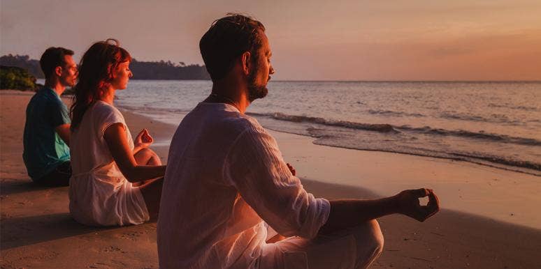 Men and women meditating on the beach Men and women meditating on the beach