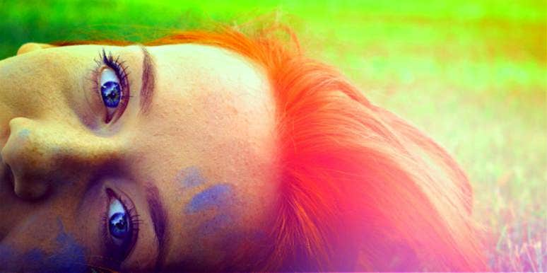 woman with bright dyed hair in a dream state looks at camera