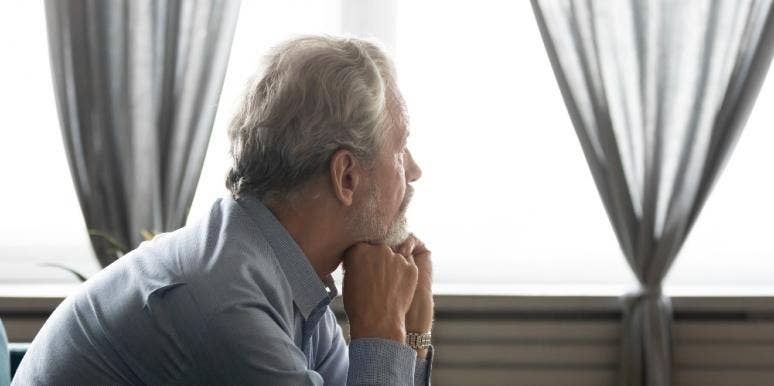 middle aged man sitting on couch looking out window