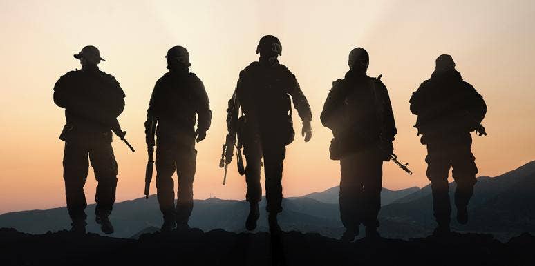 Silhouette of military members against a sunset Silhouette of military members against a sunset
