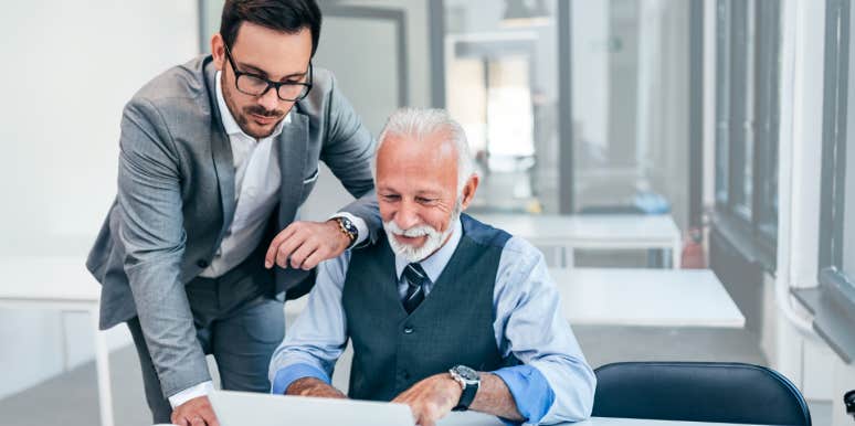 Boss helps older employee with his computer. 