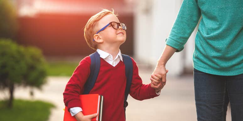 little boy holding mom's hand walking to school