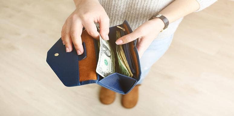 women opening wallet with dollar bills in it