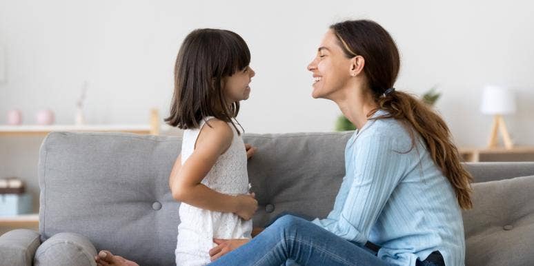 mother and little girl sitting on couch smiling