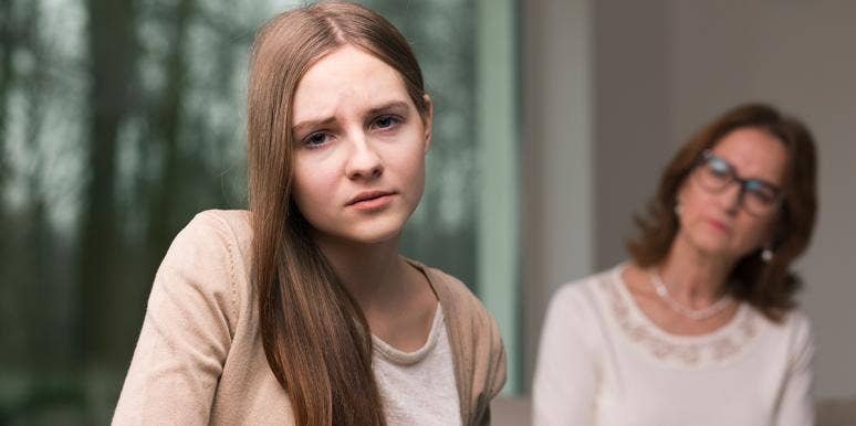 The Anti-Mother: My Mom Never Wanted To Be A Mom And It Was Obvious daughter looking strained with mom in background