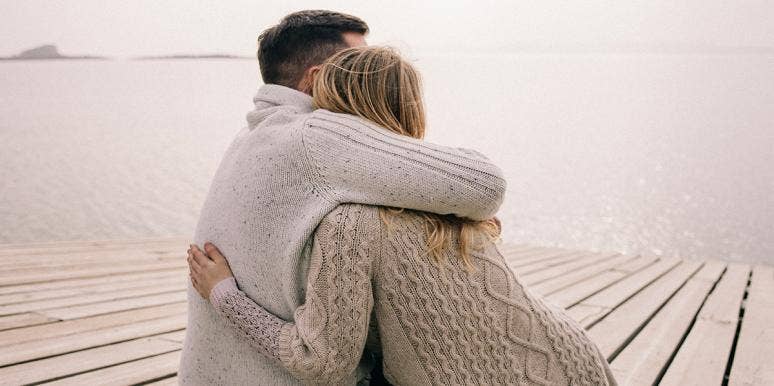 man and woman in sweaters embracing 