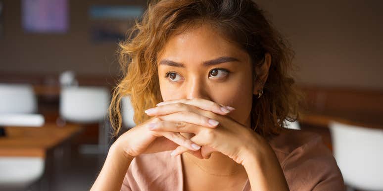 woman with hands clasped looking distraught