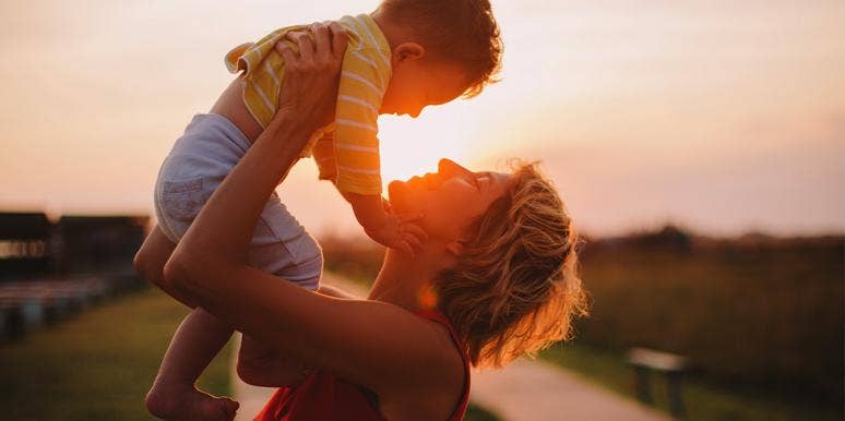 Yes, I'm A Mom Who Still Nurses My 3-Year-Old Son mom holding up baby with sunset in background