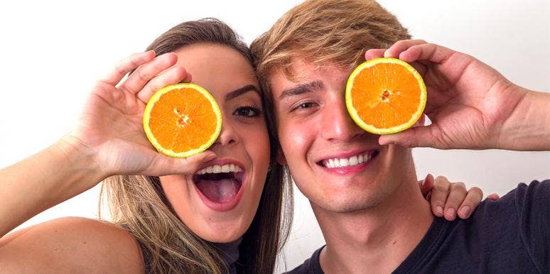 Young blonde woman and young blonde man holding oranges over their faces Young blonde woman and young blonde man holding oranges over their faces