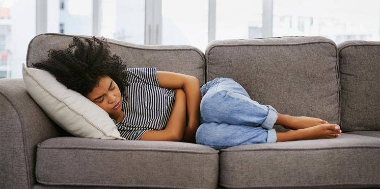 What The Age You Start Menstruating Says About You woman on couch
