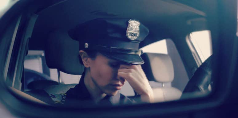 cop in the front seat of her car, looking stressed