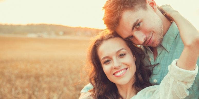 smiling man and woman cuddling at a field