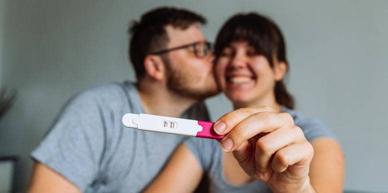 woman holding pregnancy test with husband