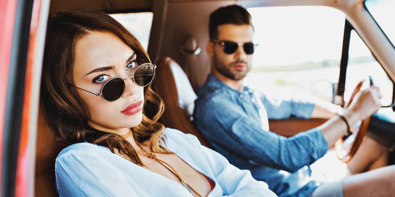 man and woman wearing sunglasses look unhappy in a car