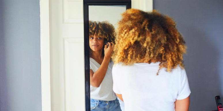This Is How I Finally Reclaimed My Femininity woman looking at herself in the mirror