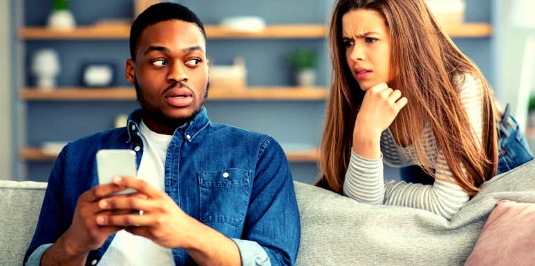 15 Red Flags In Men You Don't Want To Miss woman looking over boyfriend's shoulder while he's on his phone