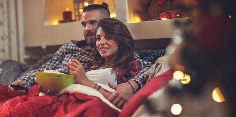 40 Best Romantic Christmas Movies To Watch With Your Love couple watching TV next to Christmas tree