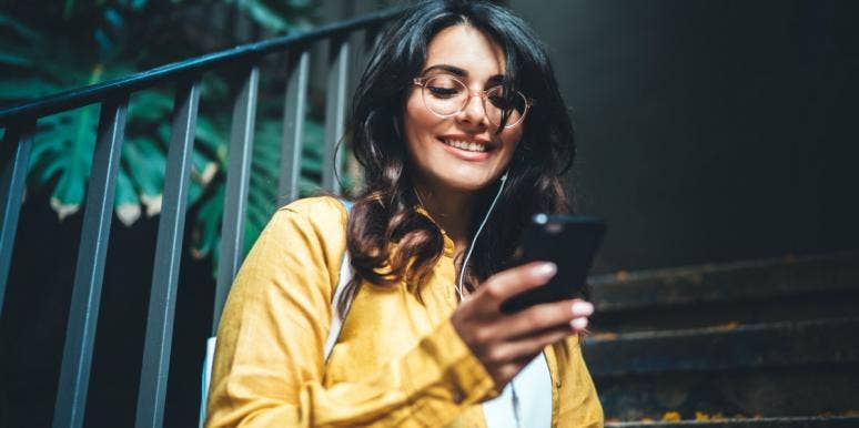woman smiling looking at phone texting