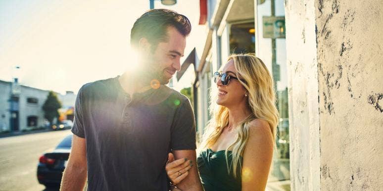 Sexual Tension Signs & What To Do If You Have It couple with lots of sexual tension flirts on the street, sun flare behind them