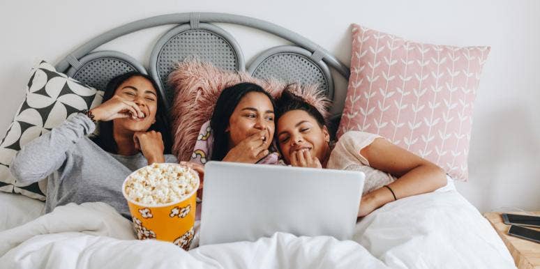 3 girls watching movies on a laptop eating popcorn